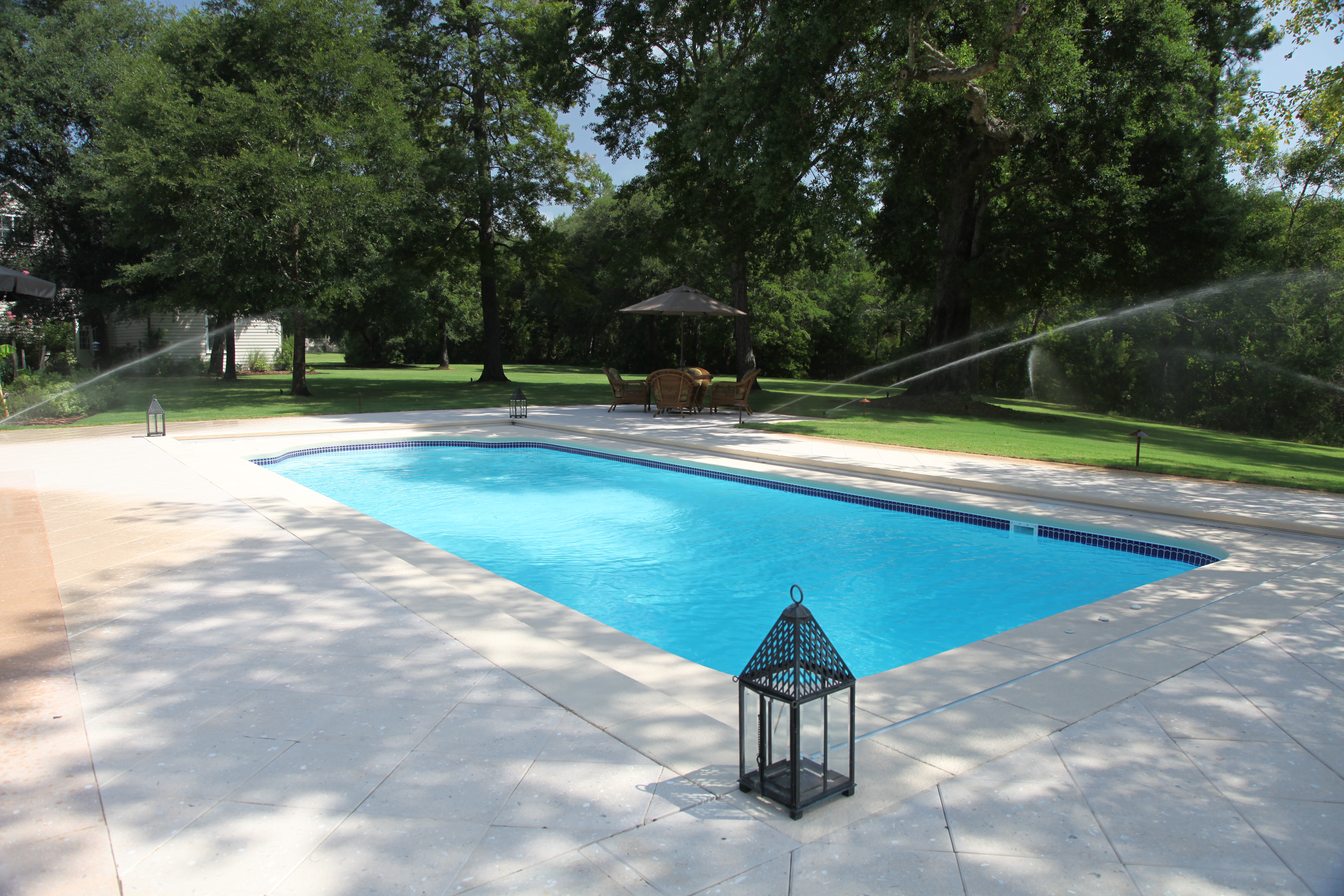 A serene backyard oasis in the desert southwest, complete with a sparkling inground pool and lush greenery. Perfect for hot summer days and warm nights under the stars.