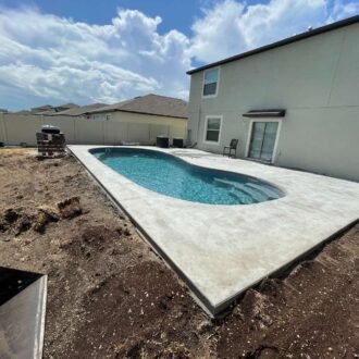 Fiberglass pool under construction in a backyard with clear turquoise water.