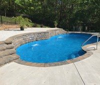 Fiberglass inground pool with turquoise water in a backyard setting.