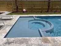 San Juan fiberglass pool in a backyard with clear turquoise water.